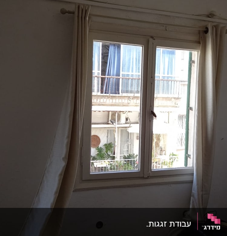 חלון זכוכית עם וילונות לבנים פתוחים